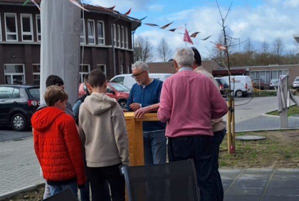 Leerlingen, vrijwilligers en bewoners zijn druk met hout voor moestuinbakken