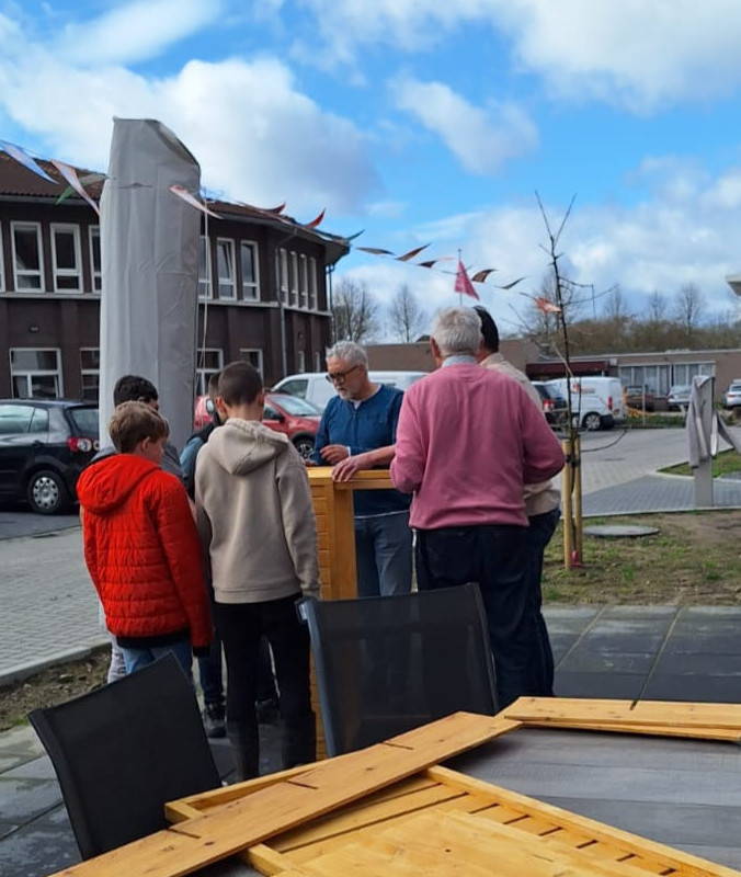 Leerlingen, vrijwilligers en bewoners zijn druk met hout voor moestuinbakken