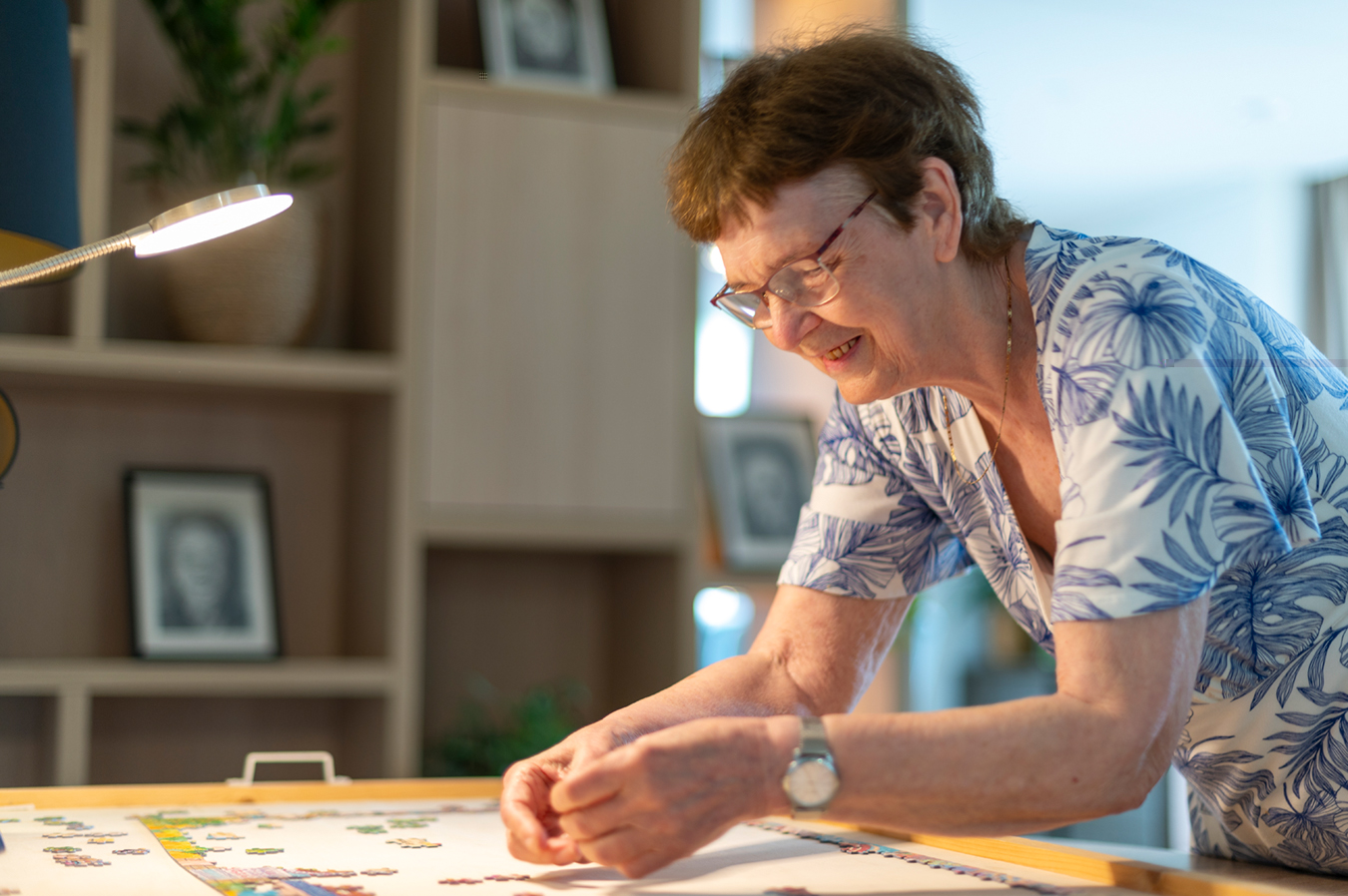 Bewoner van Huize Willibrordus in Ruurlo staat voorovergebogen over een puzzel.
