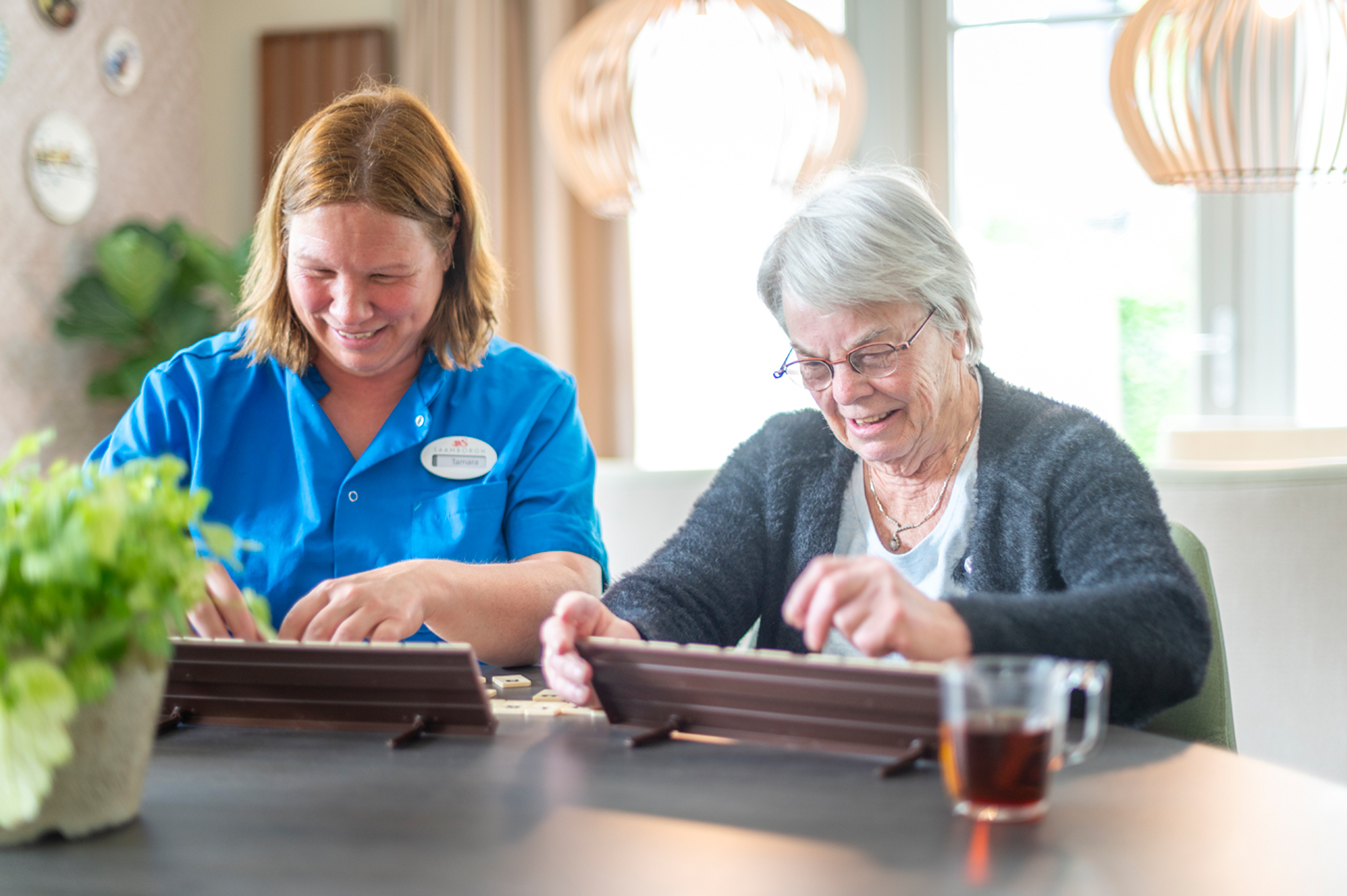 Medewerker en cliënt aan het rummikuppen onder het genot van een kopje thee
