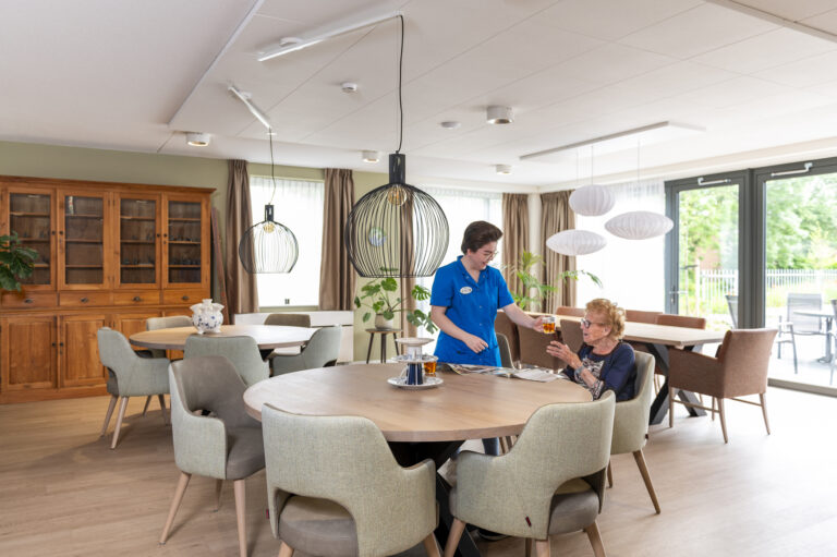 Verpleegkundige samen met cliënt bij de tafel