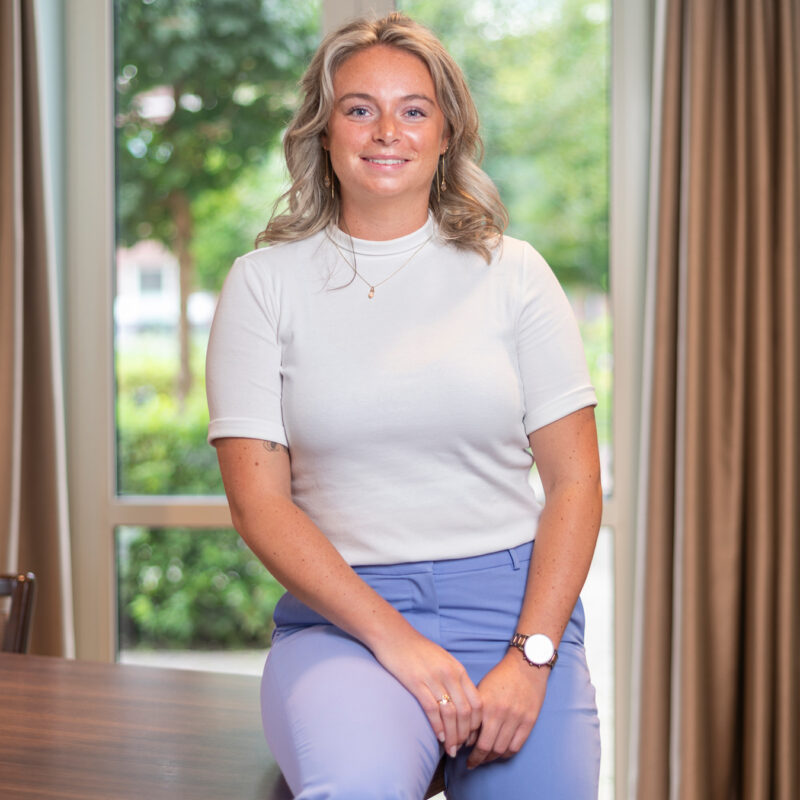 Medewerker Ilse van het hoofdkantoor zit op een hoek van een tafel.